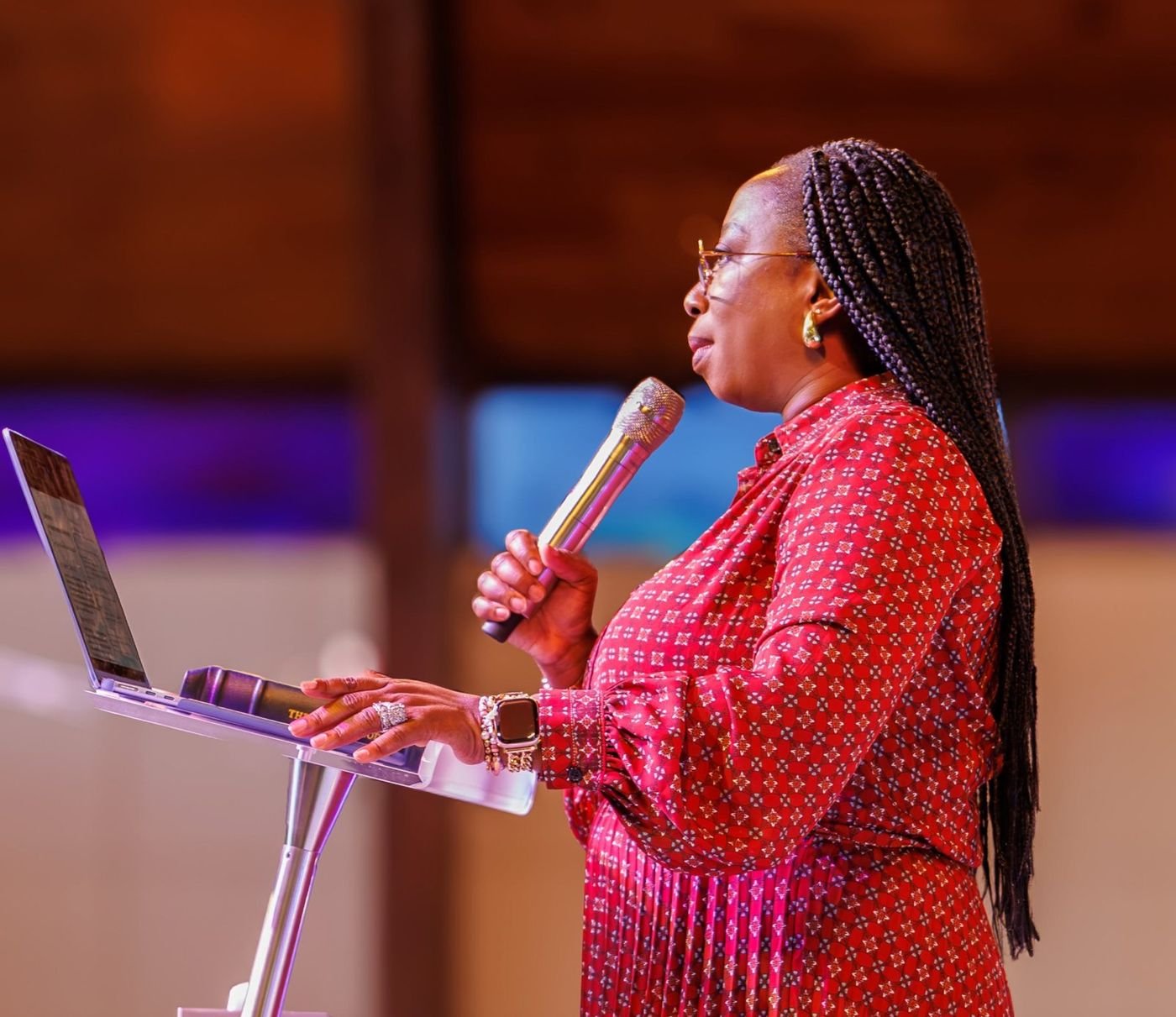 Kemi speaking at a podium, seen in profile